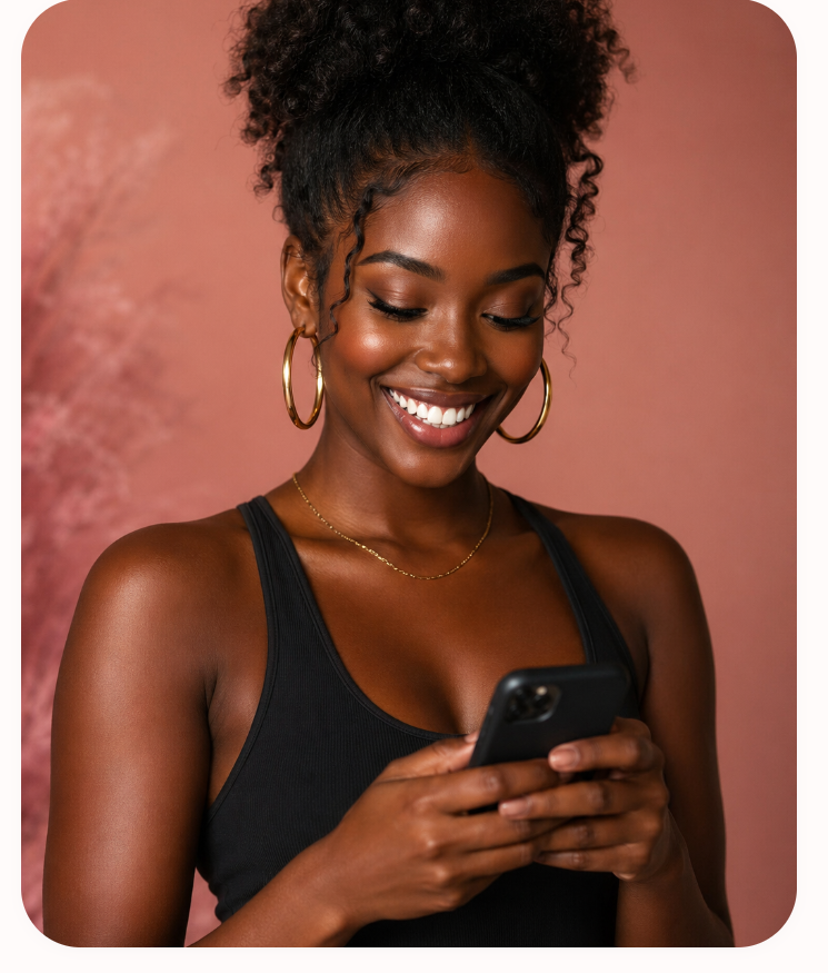 A Black woman smiling at her phone, listening to the Black Girl Maxxing audiobook.